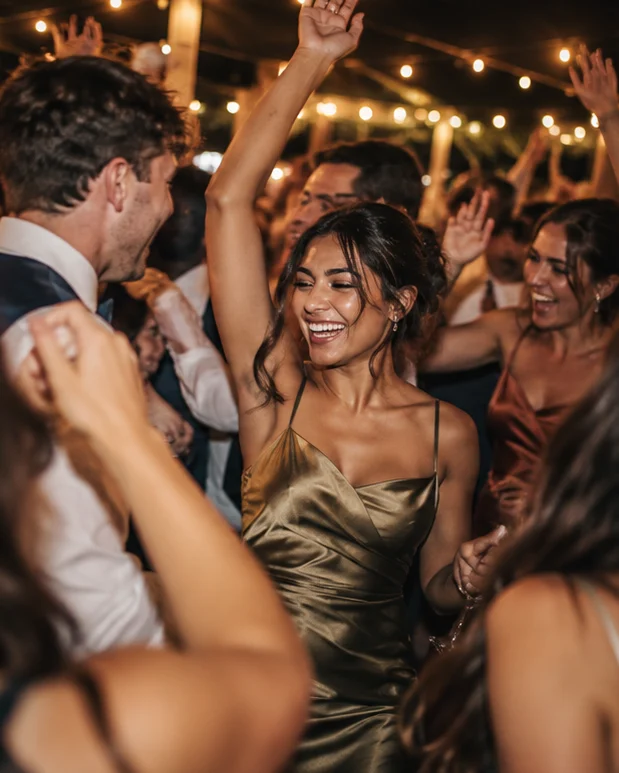 Wedding guests dancing together under warm string lights.